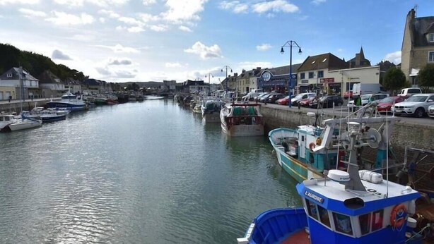 A harbor with boats docked along the waterfront, surrounded by buildings and a clear sky.