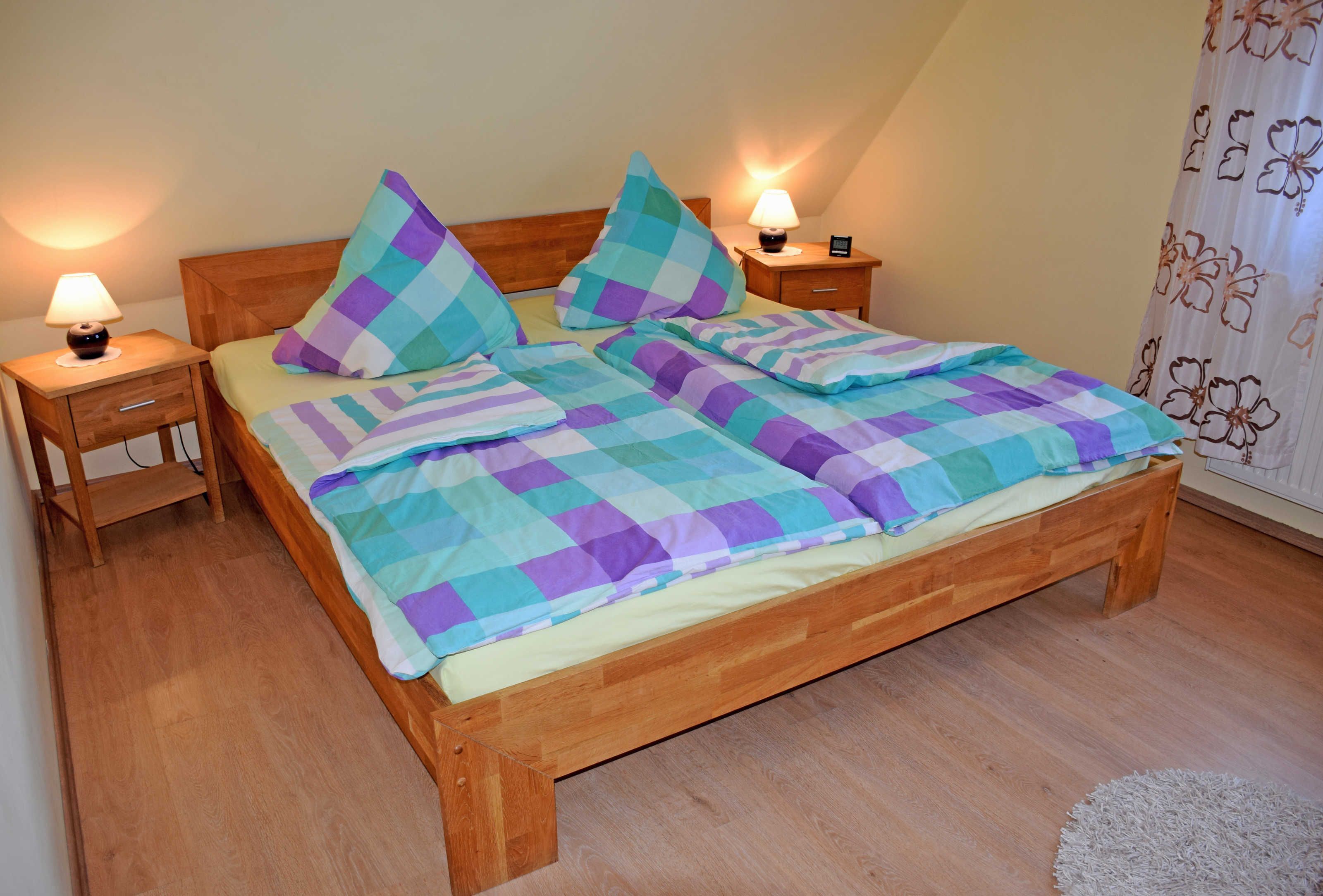 A bedroom with a wooden bed, two bedside tables with lamps, and a floral curtain.