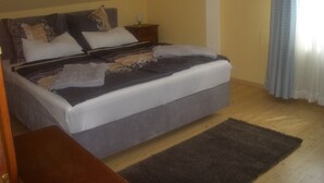Un dormitorio con cama, almohadas, una mesita de noche y suelo de madera.