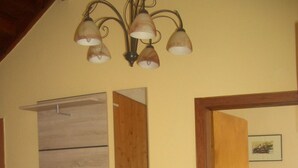 Una habitación con una escalera de madera, un banco, un espejo adosado a la pared y una puerta que da a otra estancia.