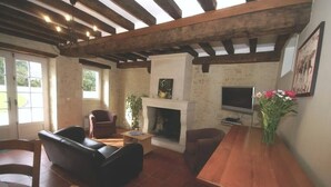 Un salon avec une cheminée, un téléviseur et des meubles en bois.