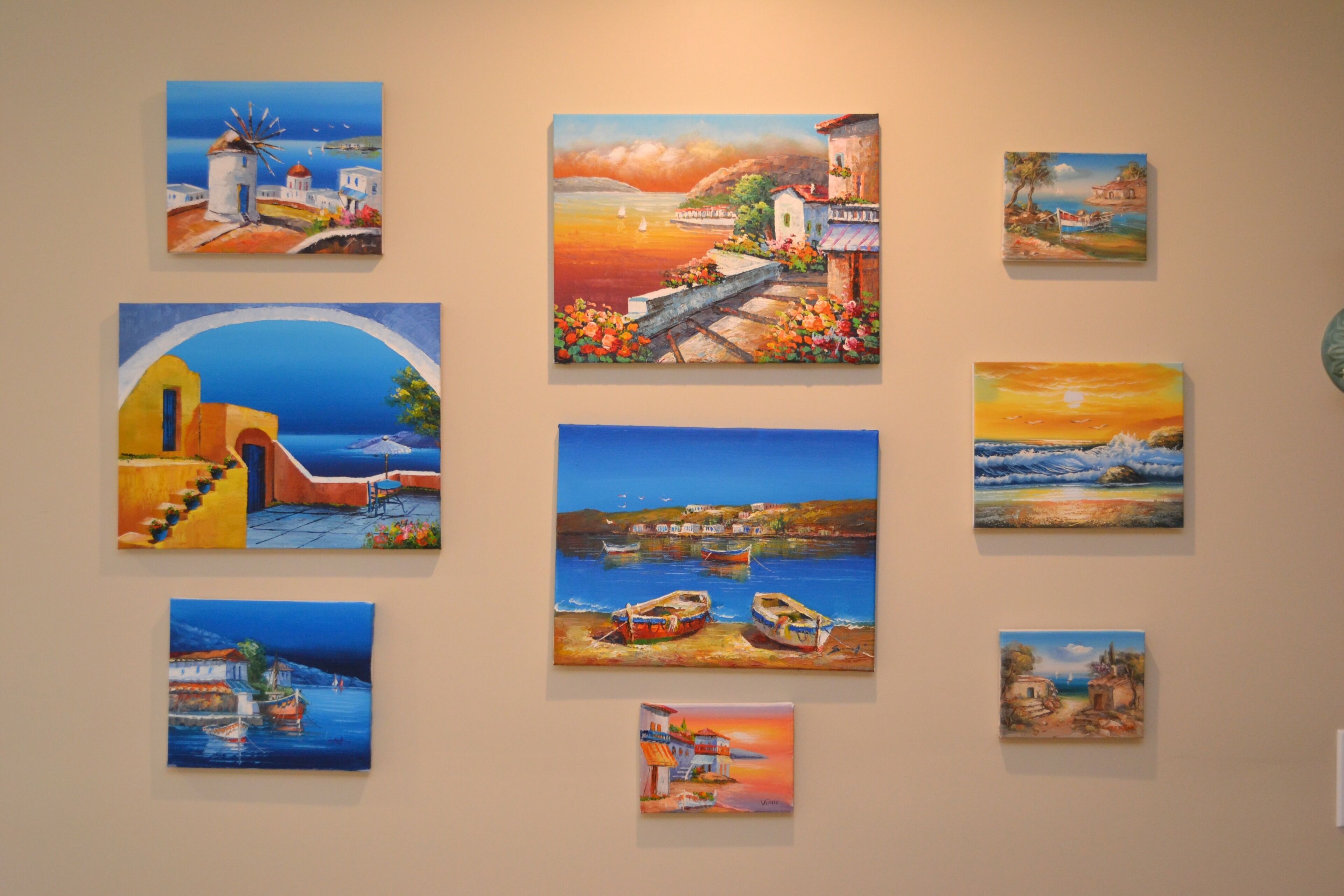 Un mur orné de plusieurs tableaux représentant des paysages côtiers.