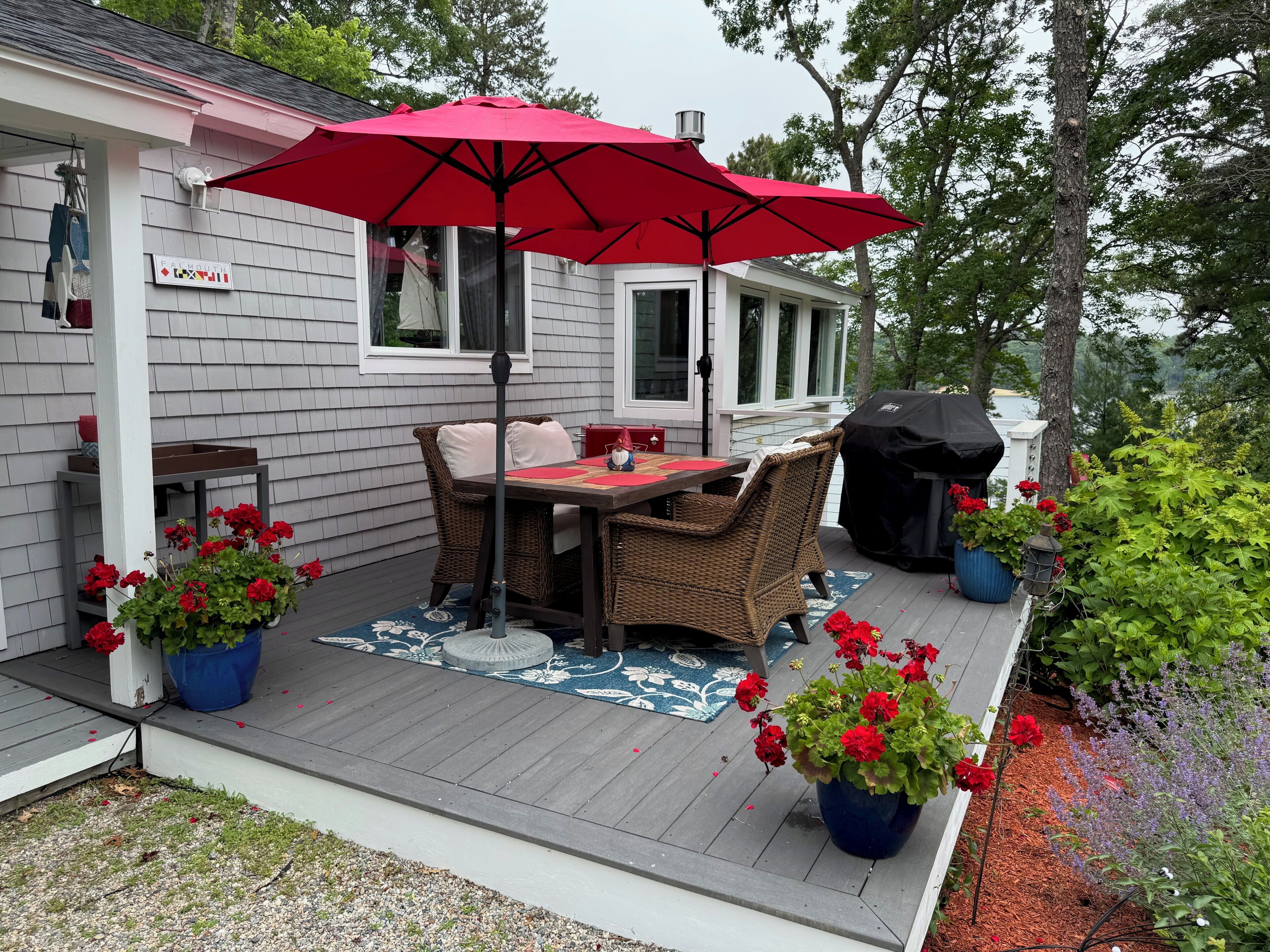 Une terrasse avec une table, des chaises et un parasol rouge.
