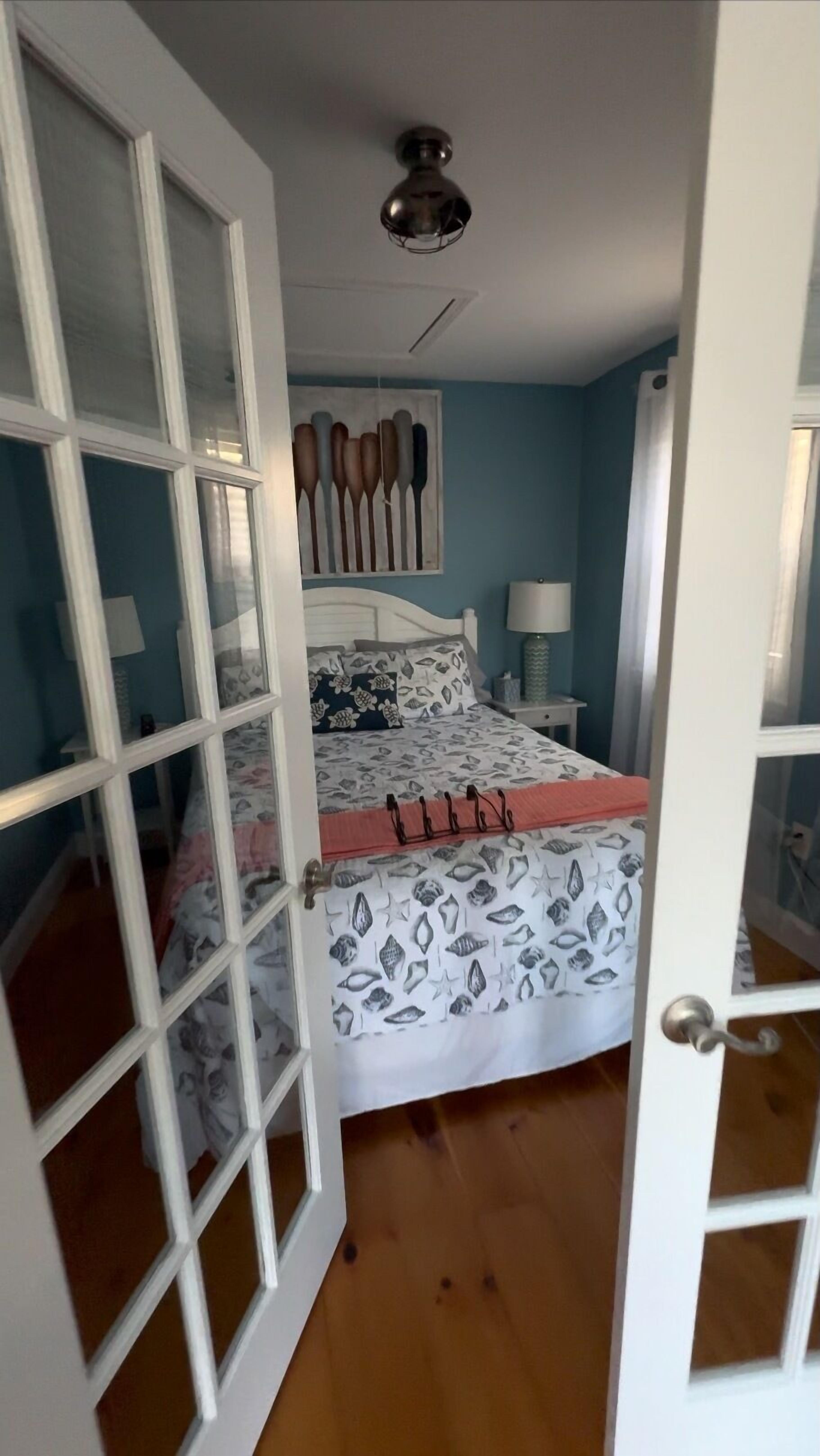 Une chambre à coucher avec un lit, un ventilateur de plafond, une table de chevet et un tableau accroché au mur.