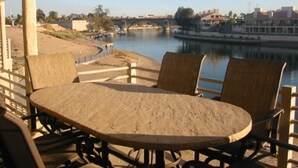 Een ronde houten tafel met vier stoelen, uitzicht op een rivier en gebouwen op de achtergrond.