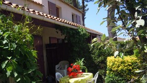 A house with a tiled roof, a garden with a table and chairs, and a hedge. - House 50 m2, terrace, enclosed garden, pine forest, private parking, shared swimming pool (Les Mathes)