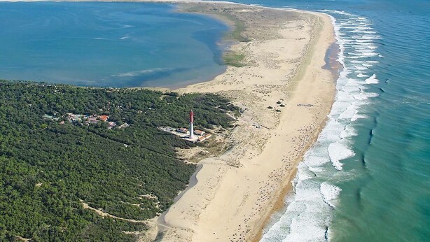 An aerial view of a coastal area with a sandy beach, a lighthouse, and a forested area. - House 50 m2, terrace, enclosed garden, pine forest, private parking, shared swimming pool (Les Mathes)