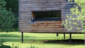A modern wooden cabin with a large window, set in a grassy area with trees in the background. - The Cube is a very private spot for an unforgettable experience by the riverside (Frénois)