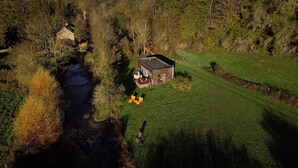 A house with a patio and a small garden, surrounded by trees and a stream. - The Cube is a very private spot for an unforgettable experience by the riverside (Frénois)