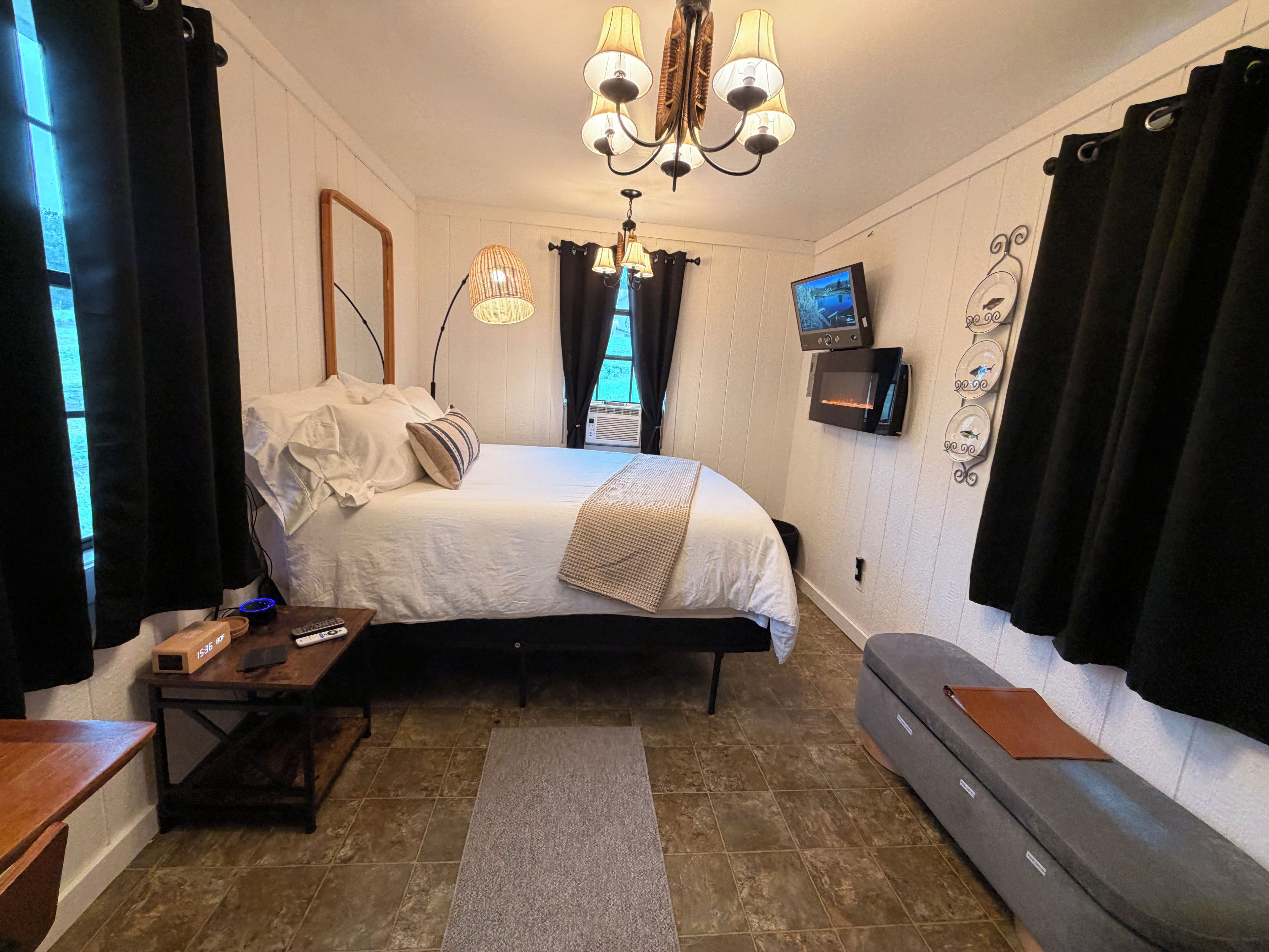 A bedroom with a bed, bedside tables, a TV, and a fireplace.