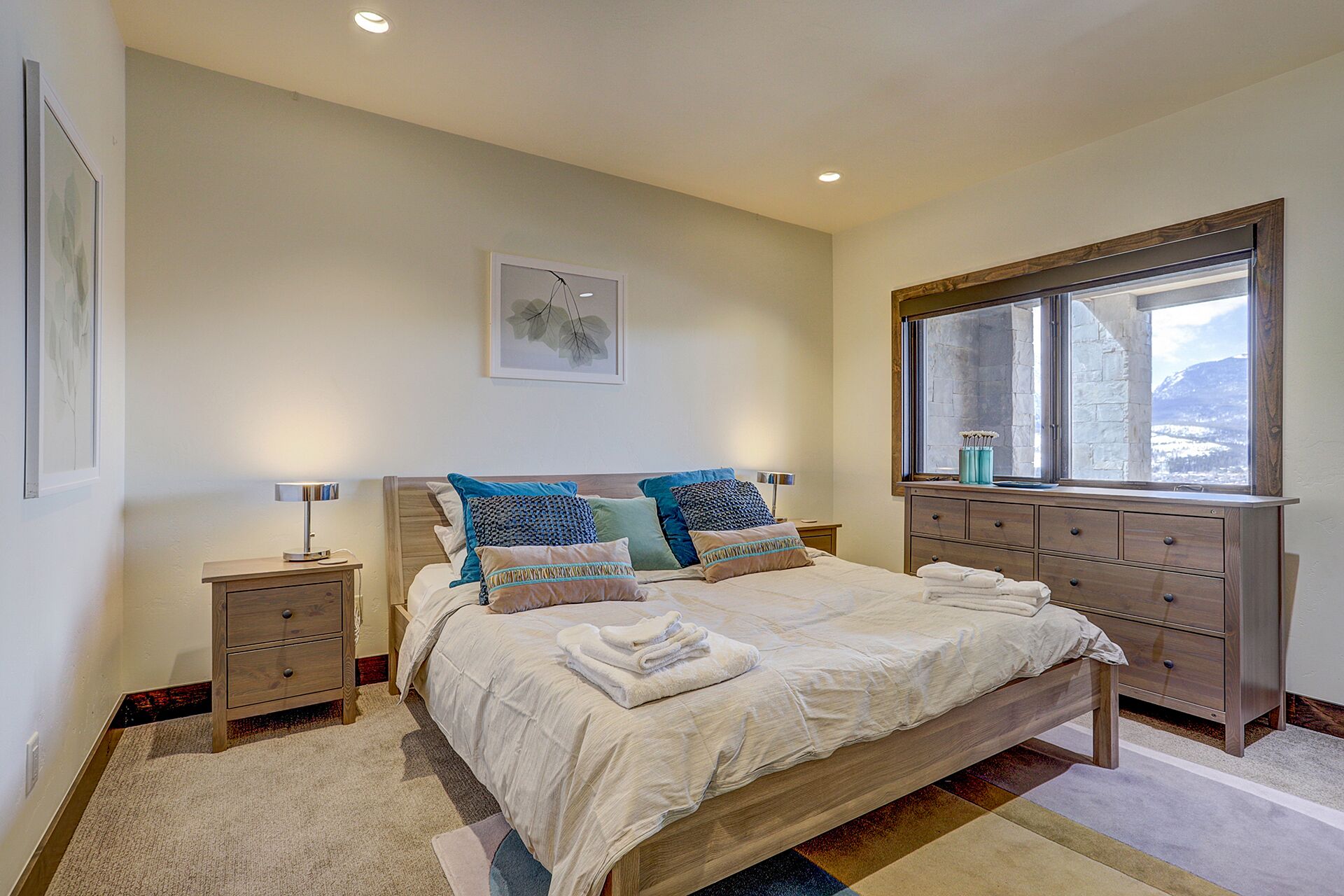 A bedroom with a bed, bedside tables, a dresser, and a window with a view.
