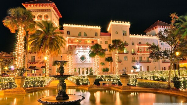 A hotel with a fountain, palm trees, and string lights. - Steps to the beach and restaurants!!! (St. Augustine)