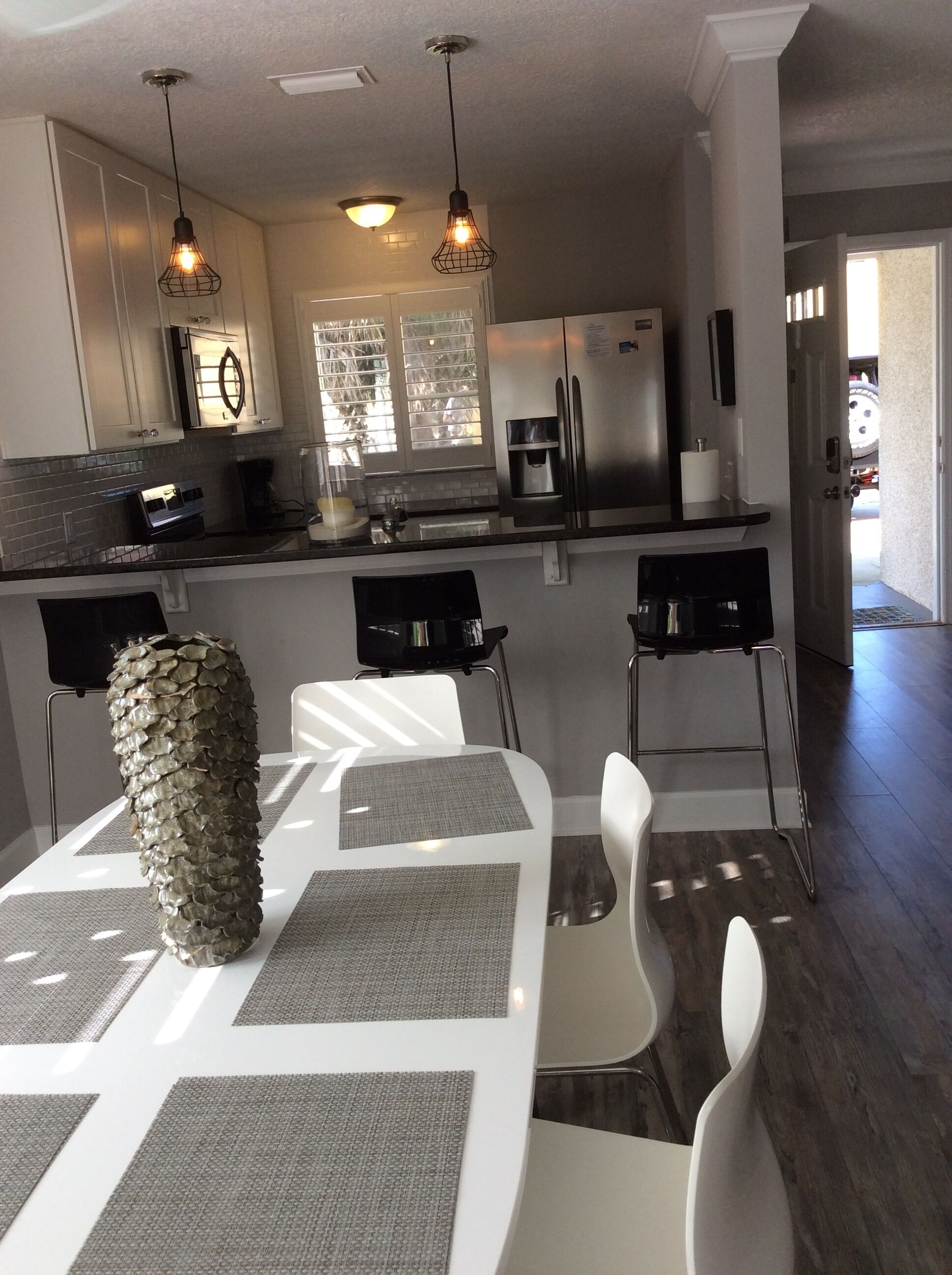 A modern kitchen with stainless steel appliances, a dining area with a unique centerpiece, and a view of the outdoors.