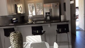 A modern kitchen with stainless steel appliances, a dining area with a unique centerpiece, and a view of the outdoors. - Steps to the beach and restaurants!!! (St. Augustine)