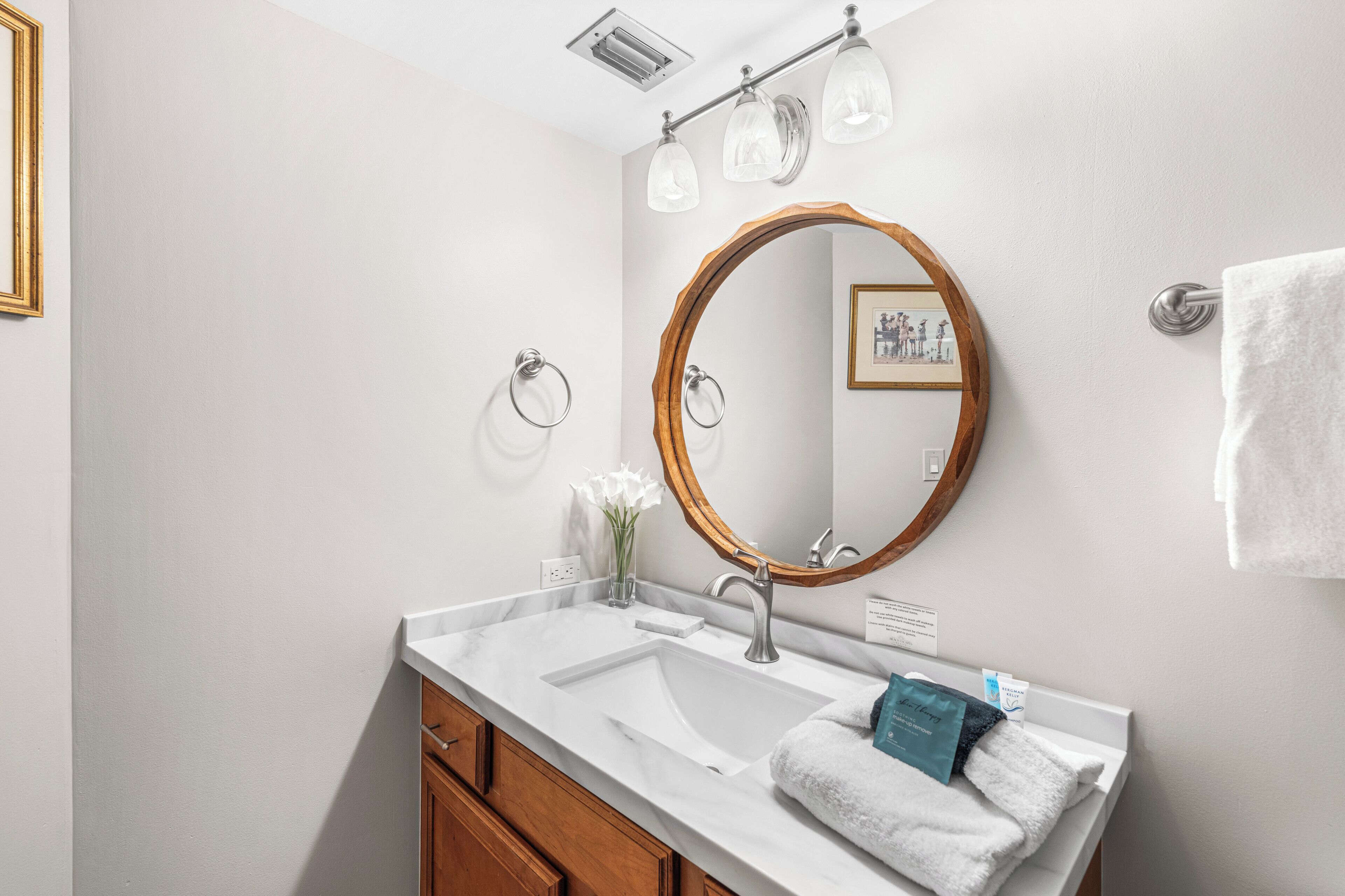 A bathroom with a white sink, wooden vanity, and a mirror with a wooden frame.
