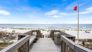 A wooden boardwalk leading to a beach with umbrellas and lounge chairs. - Spectacular Views-Gulf Front Corner unit - Hidden Dunes Gulfside 1506 (Miramar Beach)
