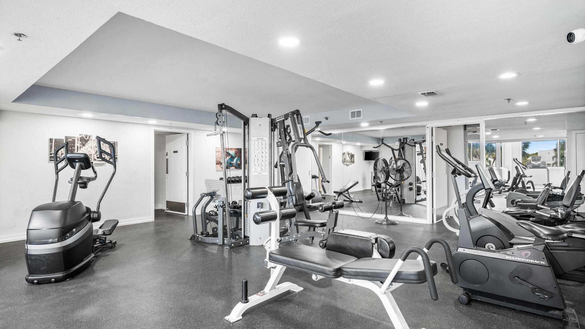 A modern gym with various exercise equipment, including treadmills, elliptical machines, and weight stations.