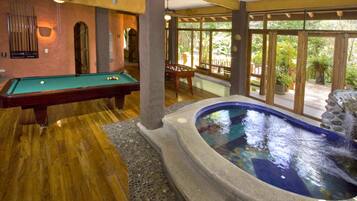 A pool table, a hot tub, and a view of the outdoors.