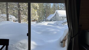 Vista a través de un vidrio de un paisaje nevado con una casa y árboles.