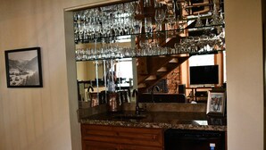 Una cocina con encimera de granito, electrodomésticos de acero inoxidable y una vinoteca.