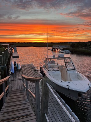 A wooden dock with a boat moored at the end, a small pier, and calm water reflecting the sunset. - Waterfront and Beach! Private Dock to Kayak, Fish or Boat the Cape and Islands! (Yarmouth)