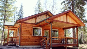 A wooden cabin with a porch, a staircase, and a garage door. - More than just a cabin... Experience Montana Adventure (Trout Creek)
