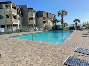 A swimming pool with lounge chairs and a lifeguard on duty.