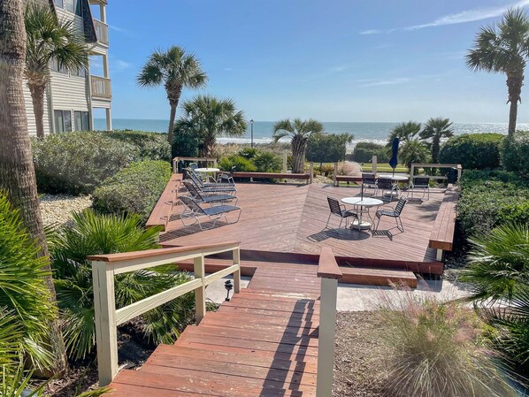 A wooden deck with outdoor seating and a view of the ocean.