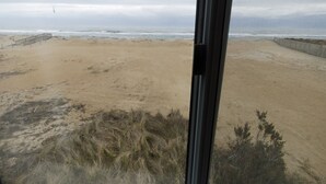 A beach view with a wooden fence and a grassy area in the foreground. - Hatteras Heaven® - Oceanfront 2BR/2 Bath Condo - Pool, Renovated Kitchen, King  (Rodanthe)