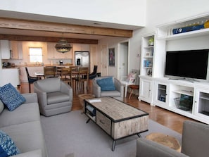 Een moderne woonkamer met een bank, fauteuils, een salontafel en een televisie.