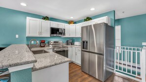 A modern kitchen with white cabinets, stainless steel appliances, and a granite countertop. -  GROUND LEVEL ON MAIN CHANNEL- WATER FRT- 4 BDRM/3 BA SLEEPS 12 WIFI (Osage Beach)