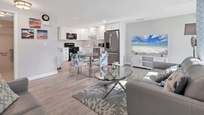 Een moderne woonkamer met een glazen salontafel, een grijze bank en een grote flatscreen-tv.