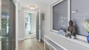 Een modern interieur met een schuifglazen deur naar een balkon, een groot raam met een Boeddhabeeld en een welkomstbord.