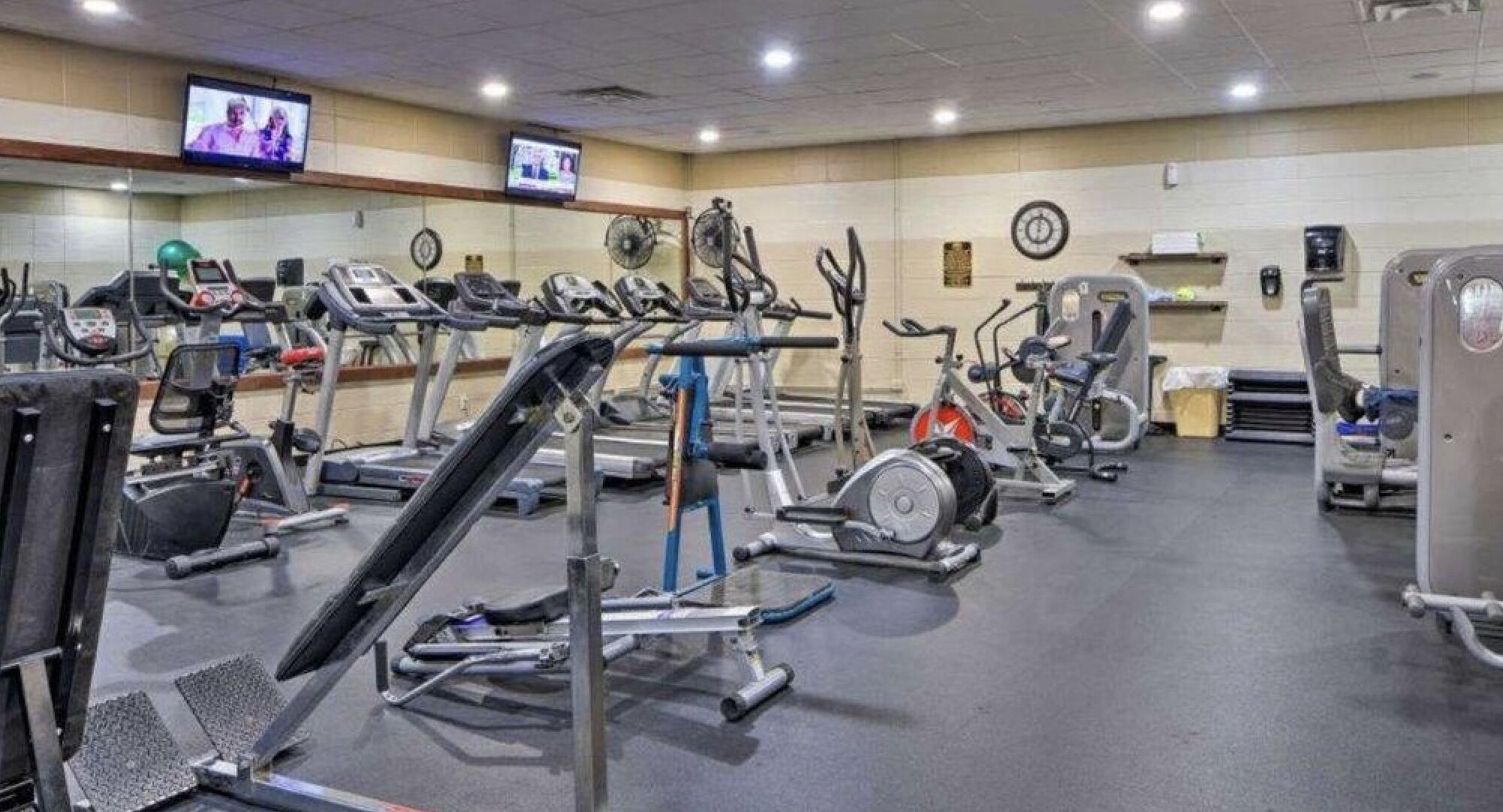 Ein Fitnessstudio mit verschiedenen Trainingsgeräten, darunter Laufbänder, Ergometer und Crosstrainer.