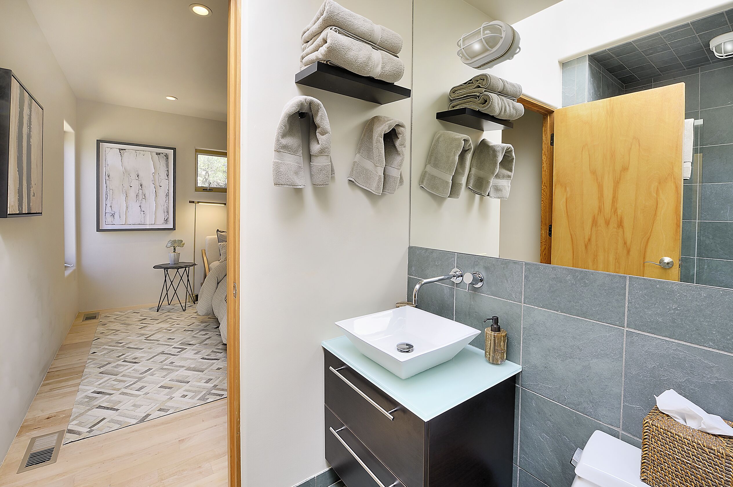A modern bathroom with a large mirror, a white sink, and neatly arranged towels.