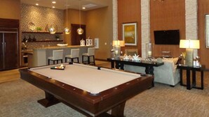 A pool table in a room with a kitchen area, a bar, and a seating area with a TV. - Gorgeous Pool View 1 Bedroom / 1 Bath Condo in The (Spring)