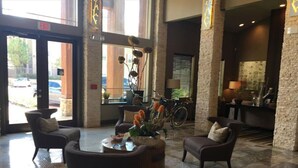 A lobby with a reception desk, several armchairs, a coffee table, and a decorative plant. - Gorgeous Pool View 1 Bedroom / 1 Bath Condo in The (Spring)