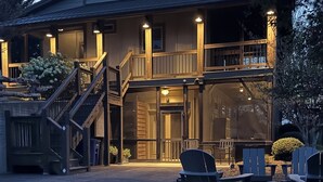 A two-story house with a covered porch, outdoor seating, and a staircase leading to the entrance.