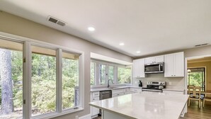 Una cocina moderna con ventanas amplias, armarios blancos y una isla central.