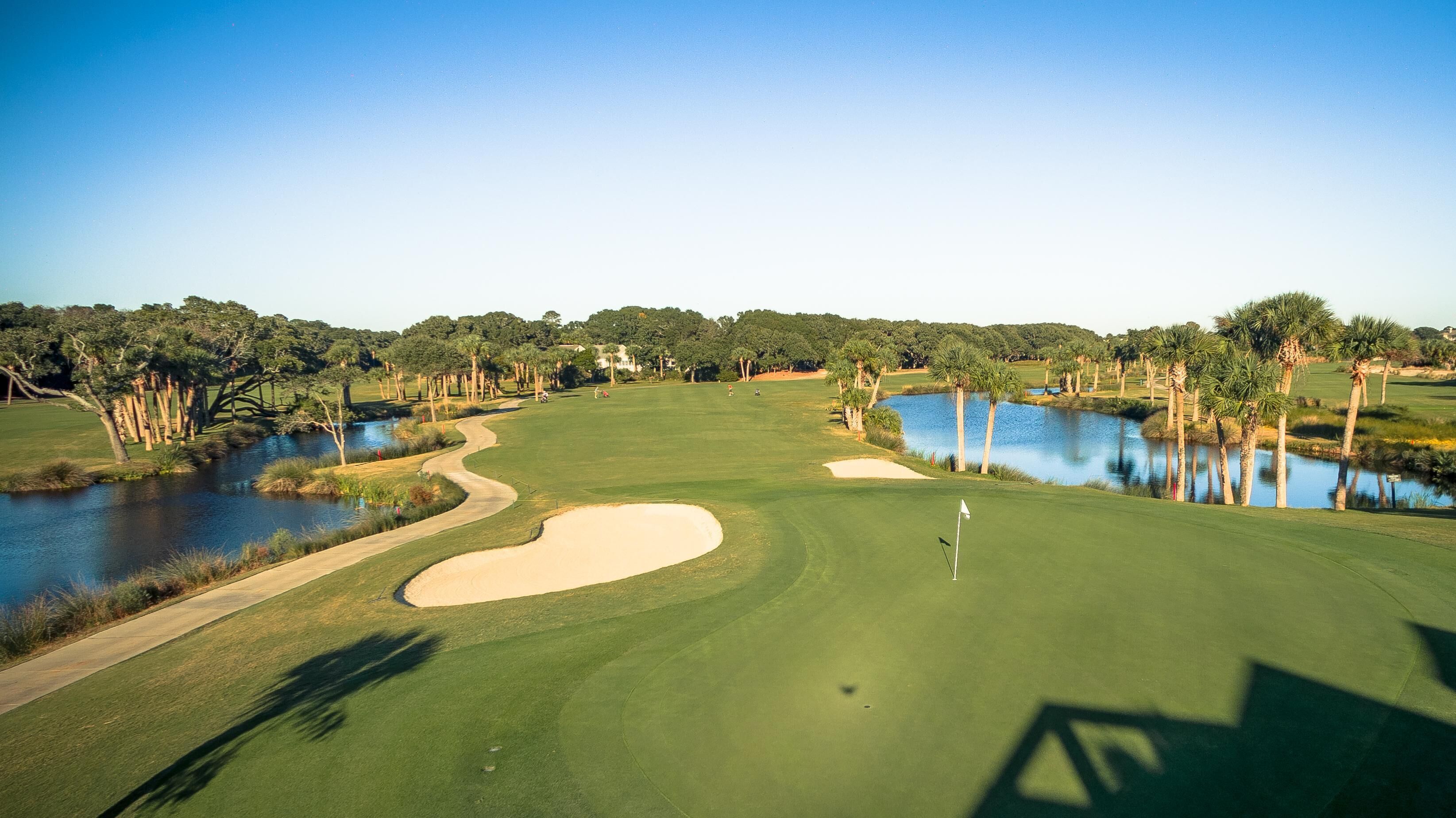 Un campo da golf con ostacoli acquatici, bunker di sabbia e un’asta di segnalazione.