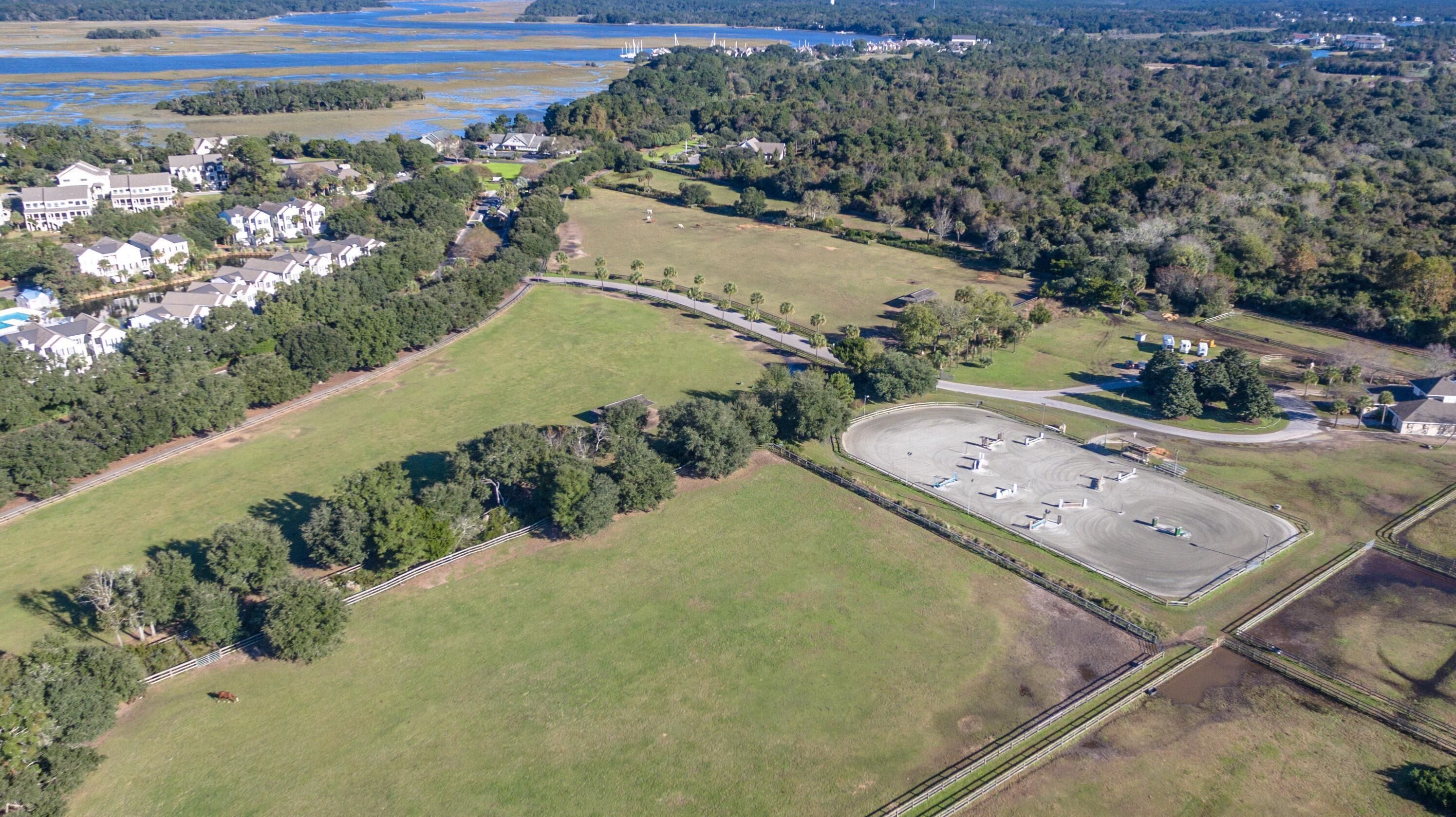 Vista aérea de una zona residencial con casas, un amplio campo verde y un estacionamiento.