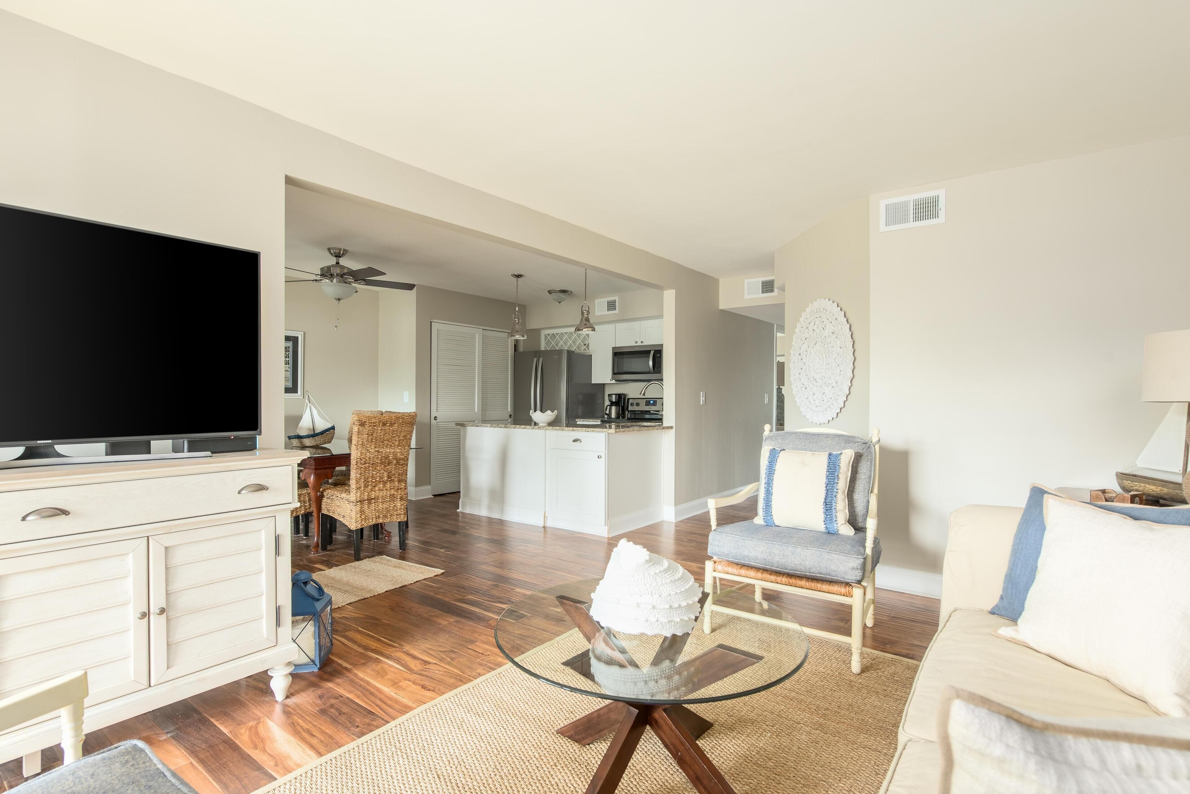 A spacious living room with a flat-screen TV, a glass coffee table, and a comfortable seating area.