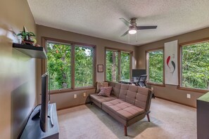 A room with a sofa, a desk, and a ceiling fan.