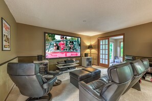 A living room with a large flat-screen TV, leather sofas, a coffee table, and a bookshelf.