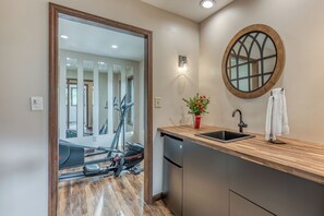 A modern kitchen with a wooden countertop, a sink, and a mirror.