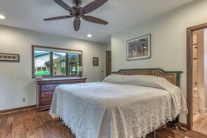 A bedroom with a bed, a dresser, a ceiling fan, a window, and a framed picture on the wall.