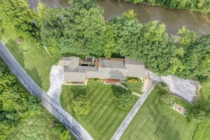 A large house with a spacious lawn and a river nearby.