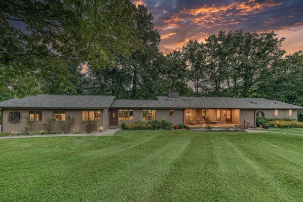 A two-story house with a large front lawn, a covered porch, and a garage.
