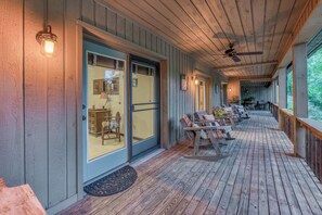 A covered porch with wooden flooring, outdoor seating, and a ceiling fan.