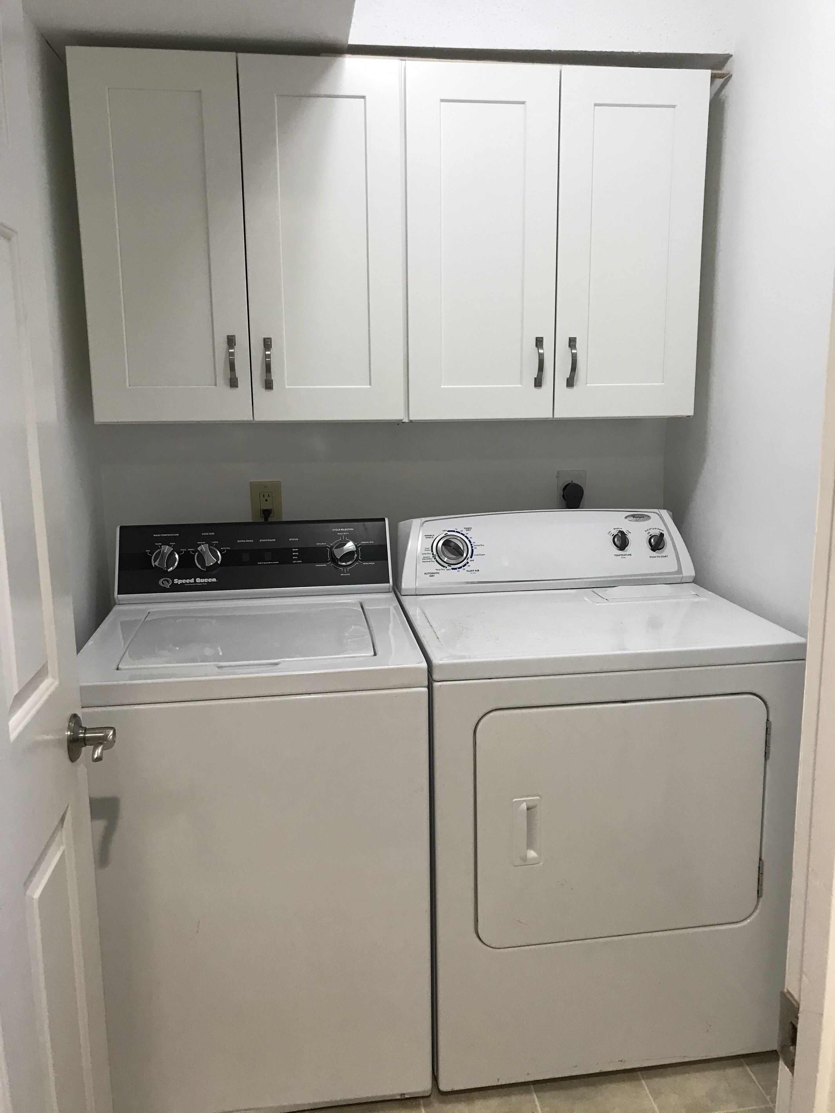 A laundry area with a front-loading washer and dryer, a stove, and cabinets above.